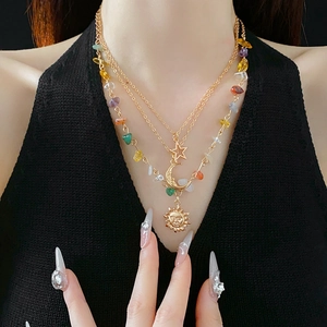 Close-up of a layered gold necklace featuring celestial sun, moon, and star pendants