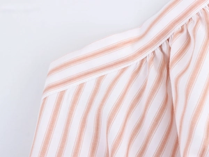 Detailed macro view of pink and orange striped cotton linen fabric with pleated shoulder design