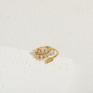 Detail of 14K gold plated leaf ring with marquise cut zircon on white stone stand