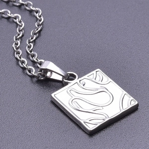 Macro detail of silver square pendant with abstract streamlined engraving on cross chain