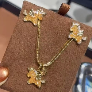 Close-up of golden unicorn jewelry set with amber zircon and diamond-like wing accents