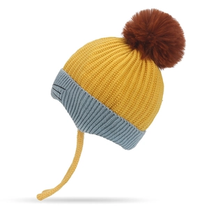 Ginger yellow knitted children's winter hat with fluffy pompom and cute ear protection