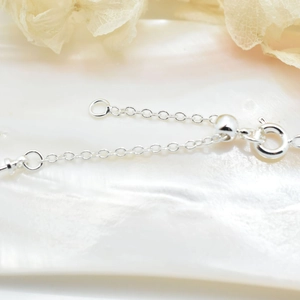 Silver DIY jewelry chain detail with adjustable slide bead and spring clasp on shell