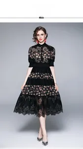 Detail of a black lace dress featuring a stand collar, polka dots, and layered lace hem