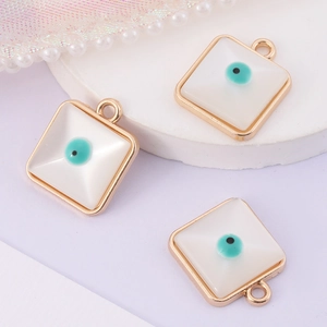 Golden square Evil Eye pendants with white base and turquoise stone on a soft purple background