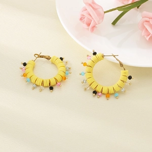 Detail of yellow resin hoop earrings with colorful beads and gold metal accents