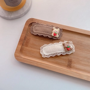 Detail of two knit BB hair clips with brown and beige lace and resin bear and rabbit charms