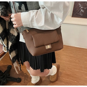 Détail du sac bandoulière marron foncé à plis avec un fermoir rotatif en métal doré