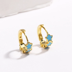 Detailed view of gold hoop earrings with vibrant blue enamel stars on white background