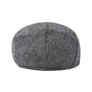 Detail view of men's flat cap featuring classic grey herringbone wool texture and stitching