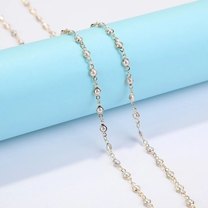 Golden eyewear chain with white pearls and crystal pendant on a light blue display stand