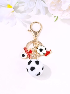 Detail of a soccer keychain with golden heart, red sneaker charm, and 3D sports ball