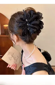 Detail einer großen schwarzen Chiffon-Blumen-Haarklammer mit Strass auf einem Damenmodell