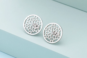 Detailed view of round hollow mandala stud earrings in polished silver titanium steel