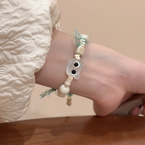 Detailed shot of handmade ceramic cat bead bracelet with woven cord and acrylic charm