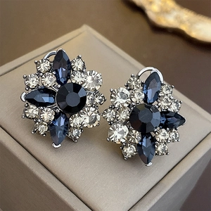 Close-up of vintage flower earrings with blue and white crystals on a jewelry box