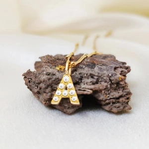 Gold stainless steel necklace featuring a pearl-inlaid letter A pendant for women.