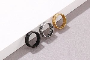 Detailed view of titanium steel rings in black, silver and gold with grid pattern texture
