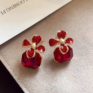 Détail de boucles d'oreilles carrées rouges avec motifs de fleurs dorées élégantes