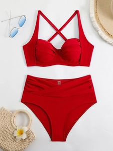 Flat lay of red two-piece bikini set with high-waisted bottoms and summer beach accessories