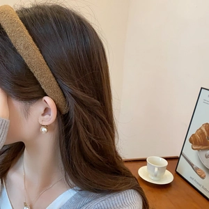 Detail showing high-cranial velvet headband and champagne gold pearl earrings on a model
