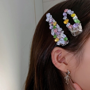 Detailed view of hair clips set and bow earring with colorful zircon and crystal