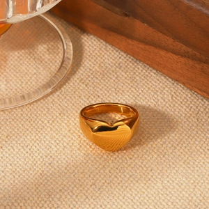 Polished 18K gold plated stainless steel heart ring shown on a rustic beige fabric background