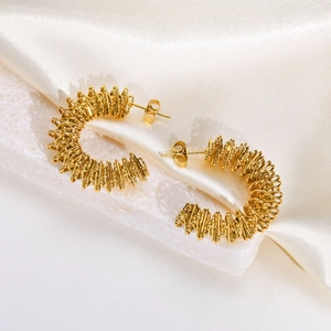 Detailed macro view of golden C-shaped hoop earrings with spiral twisted texture