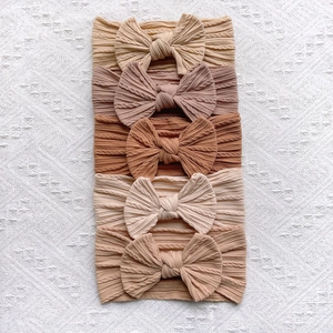 Close-up of five-piece set elastic ribbed knit baby headbands with large bows in earth tones