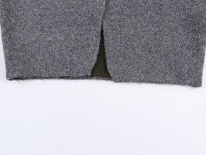 Detail shot of heavy heather grey knit jacket featuring a side slit and olive lining