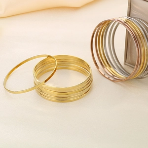 Detail of stacked titanium steel bangles in gold, silver and rose gold finishes