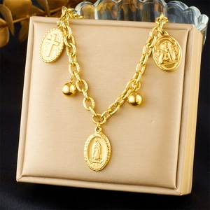 Close-up of gold-plated bracelet with Virgin Mary and cross pendants on display