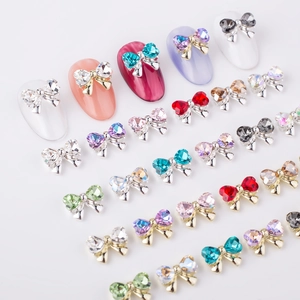 Detailed array of 3D alloy bow nail charms with colorful crystals on white surface