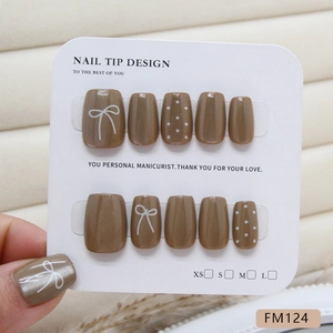 Coffee brown press-on nails featuring white hand-painted bows and polka dot patterns