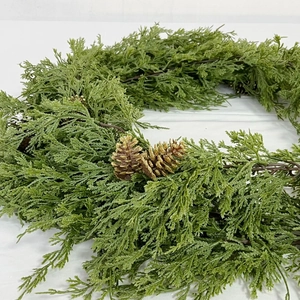 Detailed texture of green cedar wreath featuring festive golden pine cones for Christmas decor