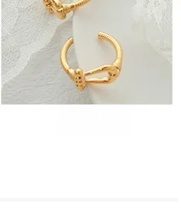 Close-up of golden U-shaped knot open ring with refined textured spiral band design