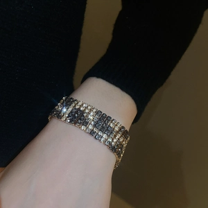 Close-up of a wide champagne and gray crystal leopard-print bracelet on a model's wrist