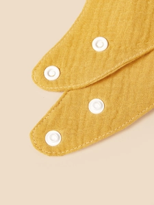Macro shot of breathable yellow cotton crepe baby bib featuring adjustable white snap buttons