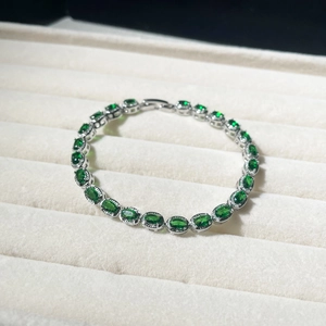 Detailed shot of a silver tennis bracelet with green oval zircon in a jewelry box