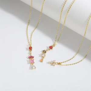 Minimalist gold necklaces with cross and colorful zircon pendants on white background