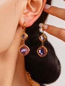Macro detail of 18K gold earrings with square purple crystals and french hooks
