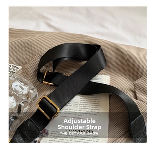 Detail of adjustable black nylon shoulder strap with gold metal buckle and leather trim