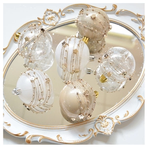 Detailed view of champagne and white Christmas mesh ornaments with stars and pearls on tray