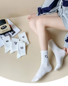 Close-up of cute white crew socks featuring unique cartoon emoji embroidery and ribbed cuffs