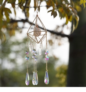 Detail of golden geometric suncatcher with crystal prisms hanging from a tree branch