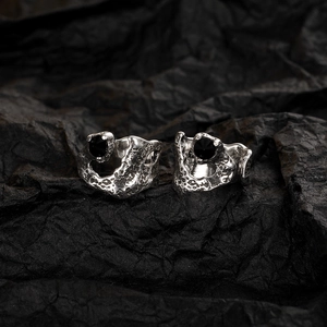 Macro shot of silver textured rings with black round gemstones on a dark background