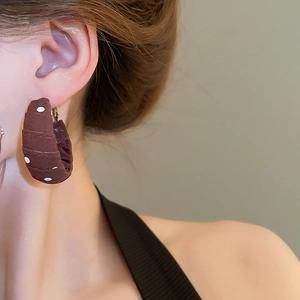 Close-up of model wearing dark brown fabric hoop earrings with white polka dots
