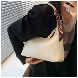 White minimalist underarm bag with a decorative geometric silk scarf on the handle