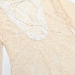 Detail of floral lace texture with beige fabric and white crochet trim on the dress