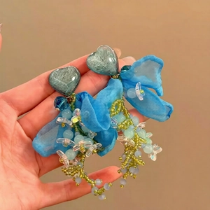 Vue détaillée de grandes boucles d'oreilles cœur vert avec nœuds en mousseline et perles
